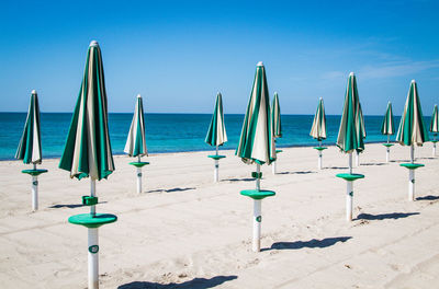 Deck chairs on beach against blue sky