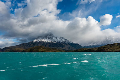 Scenic view of sea by snowcapped mountains against sky