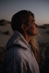 Portrait of young woman looking away against sky