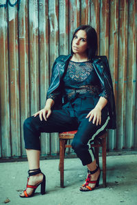 Portrait of young woman sitting against wall