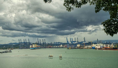 Sailboats in sea by buildings against sky