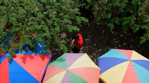 High angle view of man walking by colorful parasols on road