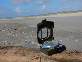 Close-up of abandoned camera on beach against sky