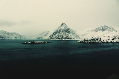 Scenic view of sea and snowcapped mountains against sky