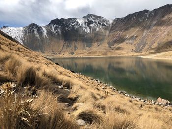 Scenic view of lake by snowcapped mountains against sky