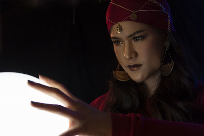 Female fortune teller with sphere against black background