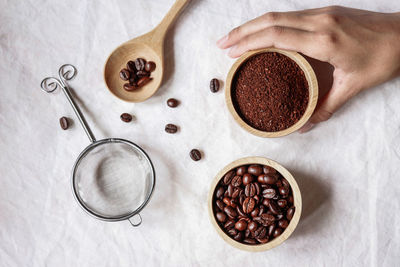 Cropped hand holding ground coffee over table