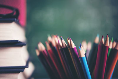 Close-up of colored pencils and books on table