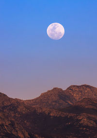 Scenic view of mountains against clear sky as full moon rises 