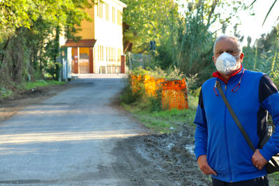 Portrait of mature man with mask on a countryside footpath.
