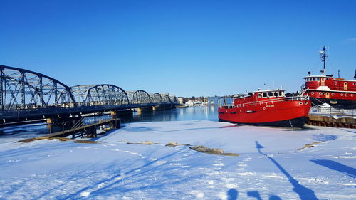 Snow covered bridge against clear blue sky during winter