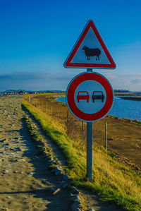 Information sign by sea against sky