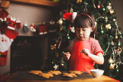 Girl preparing cookies on table during christmas