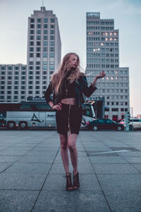 Full length of woman standing in city at dusk