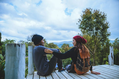 Women sitting on plants against sky