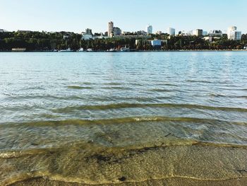 Sea by buildings against sky in city