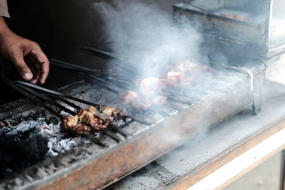 Person preparing food on barbecue grill