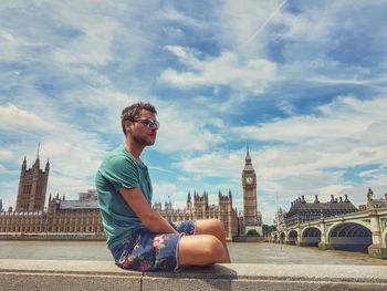 Full length of man sitting on bridge over river