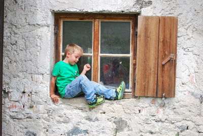 Side view of woman sitting on wall