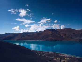 Scenic view of lake and mountains against blue sky