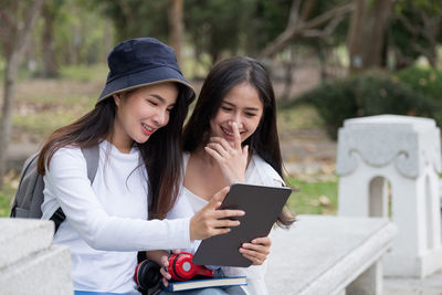 Asin female students wearing casual clothes sitting at outdoor having deep looks in books. cute