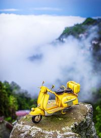 Close-up of yellow toy by rock against sky