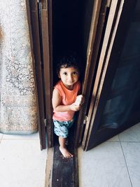 Portrait of boy holding food by door at home
