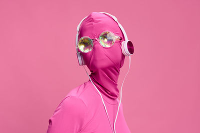 Portrait of woman wearing mask against pink background