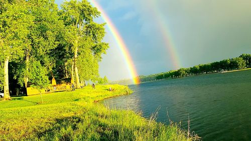 Scenic view of rainbow over river against sky