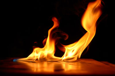 Close-up of burning candle against black background