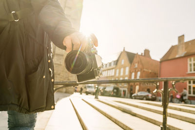 Man holding umbrella in city against sky