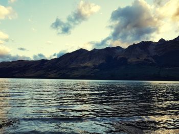 Scenic view of sea by mountains against sky