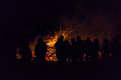 Silhouette people standing against bonfire at night