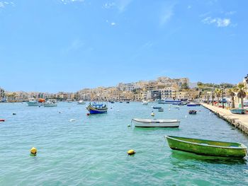 Boats moored in sea against clear blue sky