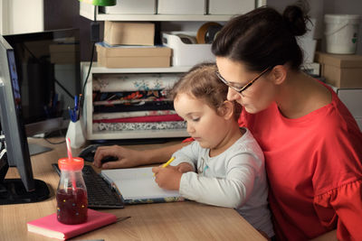 High angle view of girl using laptop on table at home