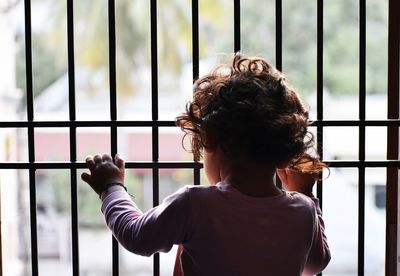 Rear view of boy standing against window