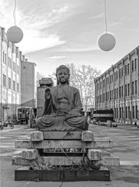 Buddha statue in city against sky