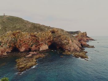 Rock formations by sea against sky