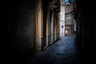 Man walking in alley amidst buildings