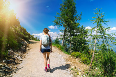 Rear view of woman walking on road against sky