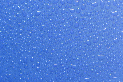 Full frame shot of wet bubbles against blue background
