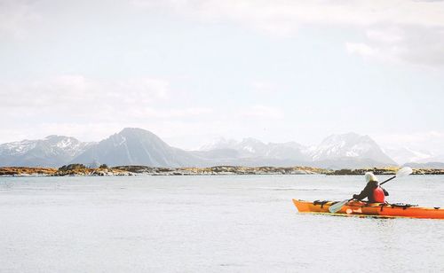 Scenic view of sea by snowcapped mountains against sky