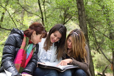 Young woman sitting on book in forest