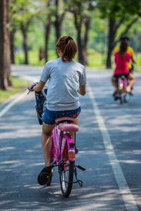 Rear view of woman riding bicycle on road