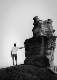 Rear view of woman standing by rock formation