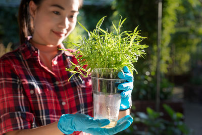 Young woman holding plants in nursery