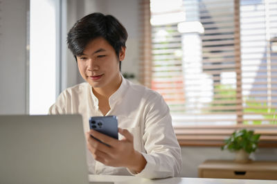 Young woman using mobile phone at home