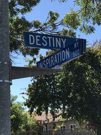 Low angle view of information sign against trees in city