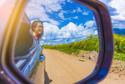 Reflection of man on side-view mirror