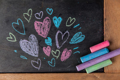 Close-up of colorful heart shape chalk drawings on blackboard